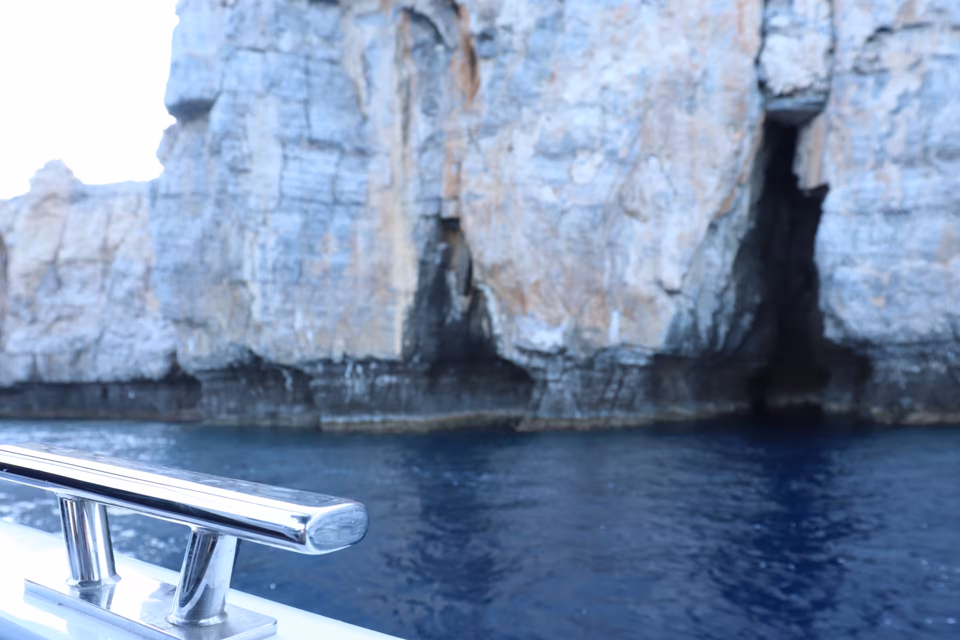 Bayliner M17 bow rail facing coastal sea caves and blue water on a 2-hour cave and snorkelling experience