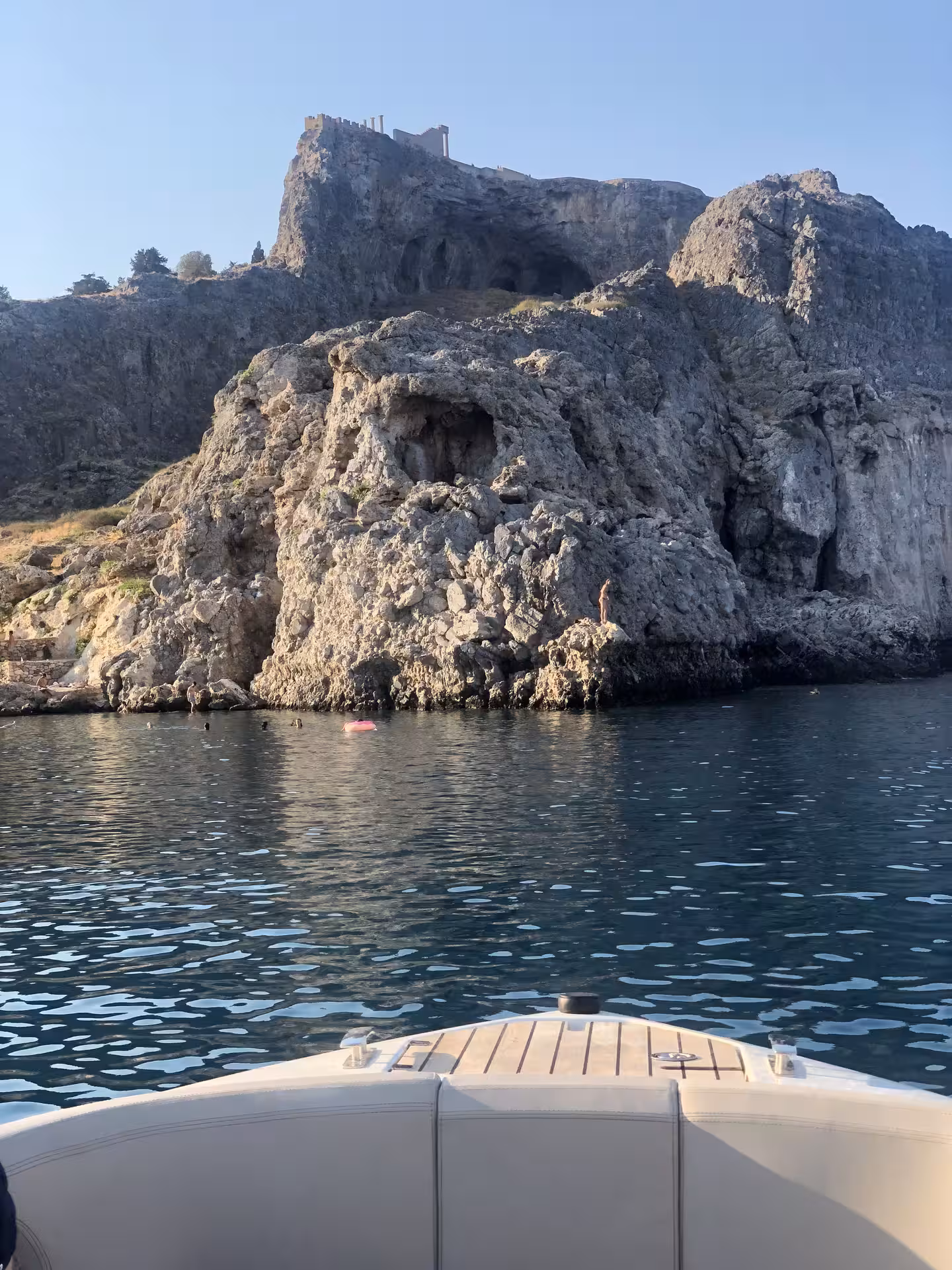 Bayliner M17 approaching rocky sea caves for a 2-hour cave and snorkelling experience, clear water and cliffs ahead