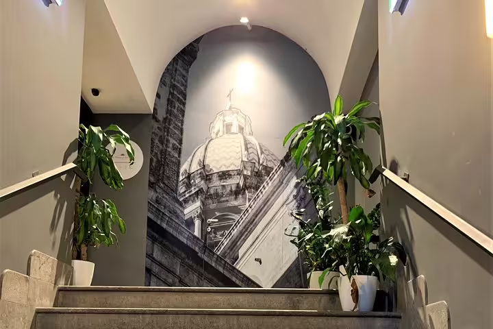Staircase interior of B&B Hotels Palermo Quattro Canti with dome mural and greenery, welcoming Palermo airport transfer guests