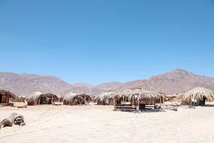Bedouin desert camp huts with mountain backdrop in Marsa Alam, stop on sunset ATV quad safari trip