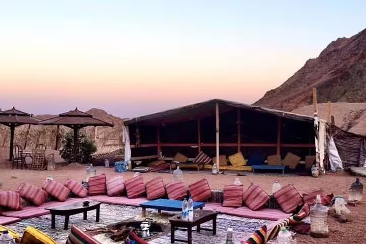 Bedouin desert camp near Hurghada at sunset with cushions and tables for dinner and traditional show