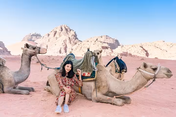 Traveler relaxing by camels in Marsa Alam desert, a Bedouin night jeep safari with dinner and stargazing