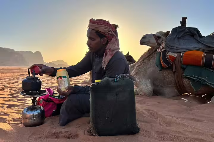 Bedouin guide brewing tea beside camel at sunset in Sinai, Sharm El Sheikh quad safari with dinner
