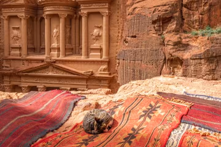 Traditional Bedouin rugs at Petra with carved temple backdrop, Jordan day trip from Sharm El Sheikh
