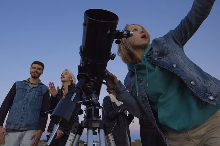 Group using a telescope for desert stargazing near Marsa Alam on a Bedouin night jeep tour with dinner