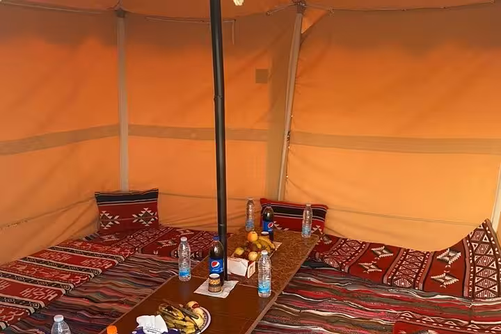 Traditional Bedouin-style tent lounge with rugs, cushions and snacks, eco camp setup in Bahariya Oasis, Egypt