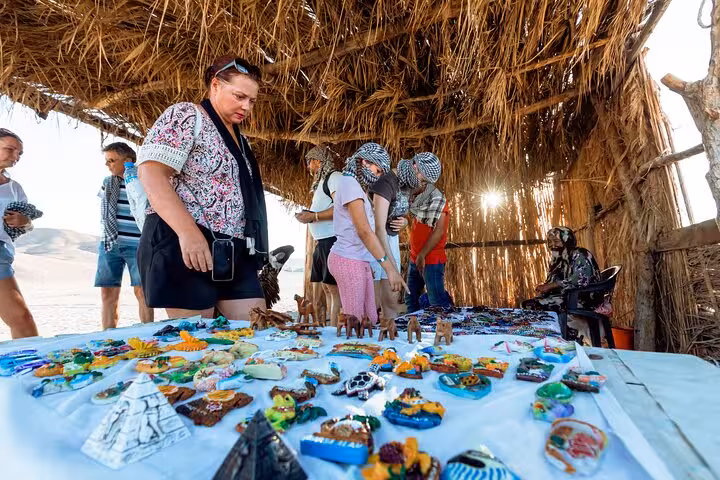 Tourists browse handmade souvenirs in a Bedouin village hut on Marsa Alam quad safari with dinner stop