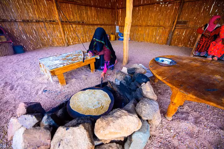 Bedouin woman baking flatbread in desert hut during Hurghada Jeep Super Safari to Bedouin village with dinner