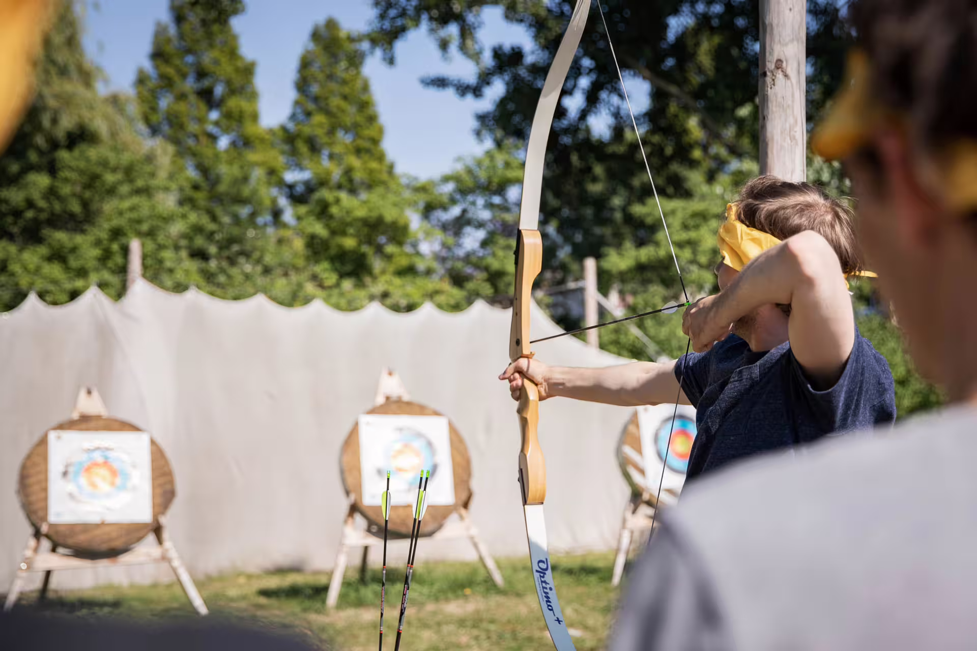 Beginner archer aiming a recurve bow at outdoor targets during archery experience in Amsterdam