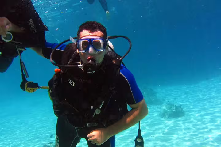 Beginner scuba diver underwater with instructor in clear blue sea during intro diving and snorkeling day trip