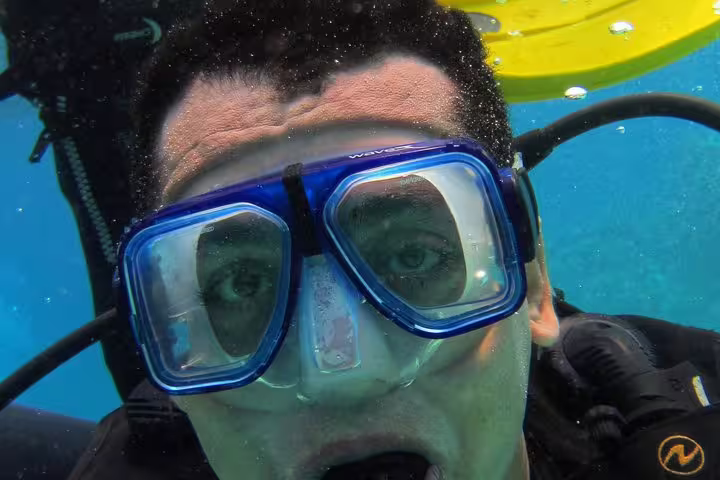 Beginner scuba diver underwater with blue mask on intro diving and snorkeling day trip in clear sea