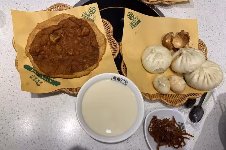 Traditional Beijing breakfast with savory pancakes, steamed buns, and soy milk on a sidecar food tour.