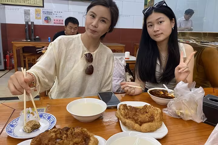 Two women enjoying traditional Beijing breakfast dishes during a sidecar food tour in a local eatery.
