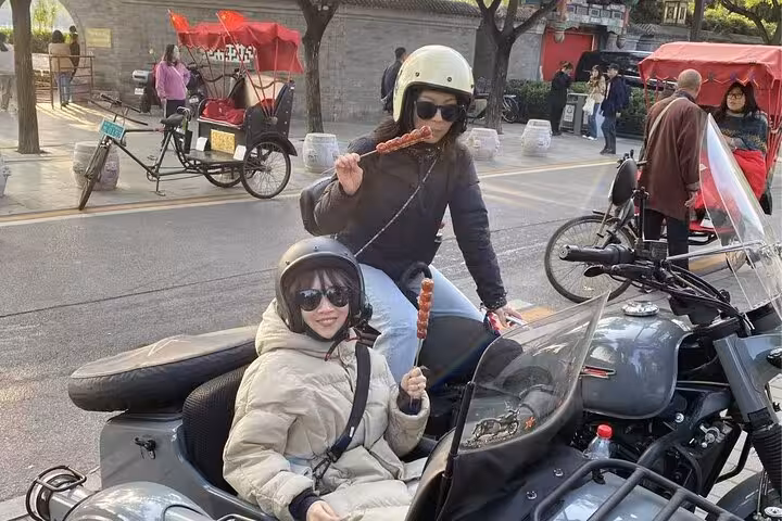 Tourists savor local skewers while riding a sidecar through scenic streets on a Beijing food adventure.