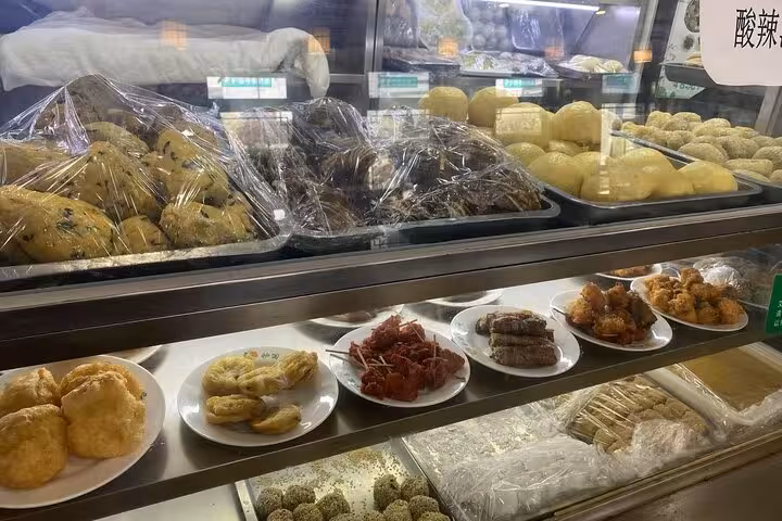 Display of diverse local snacks and pastries in a Beijing bakery, part of the Sidecar Food Tour experience.