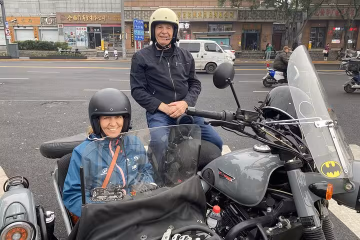 Smiling tourists ready for a thrilling Beijing sidecar tour to explore local flavors and sights.