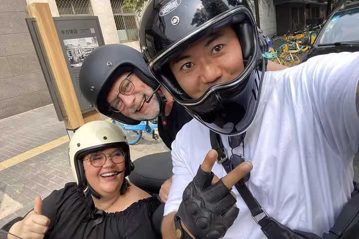 Smiling adventurers take a selfie during a thrilling Beijing sidecar tour, highlighting a memorable and fun urban exploration.
