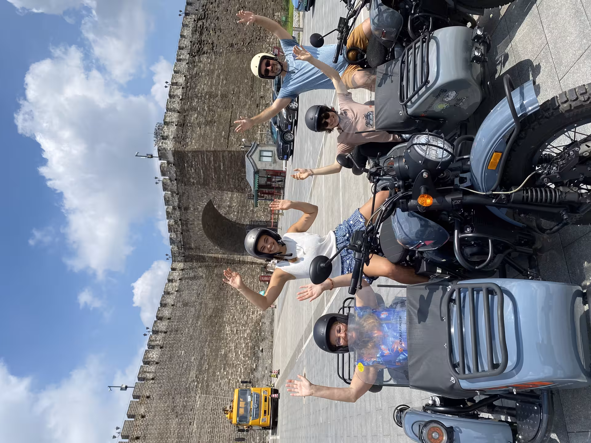 Group of travelers on sidecars waving in front of Beijing's ancient city wall during the Pearl Market tour.
