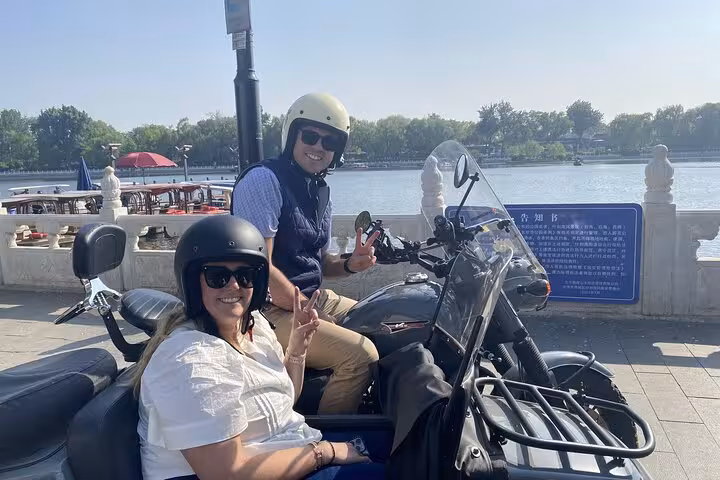 Couple on a Beijing sidecar tour by a scenic lake, capturing the essence of the city's ancient and modern blend.