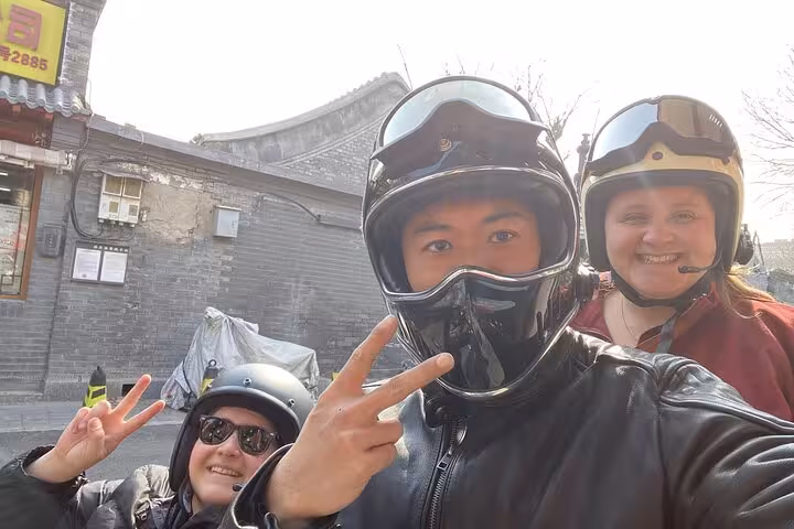 Tourists in helmets enjoy a sidecar ride through Beijing's historic streets on the Ancient & Modern Sidecar Tour.
