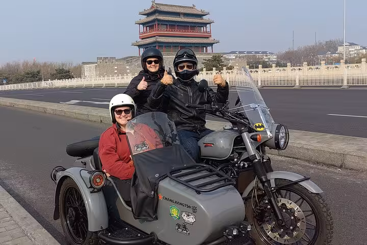 Tourists enjoy a Beijing sidecar adventure with historic architecture backdrop, perfect for a private 4-hour discovery tour.
