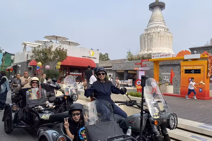 Tourists on sidecars explore Beijing's historic streets near a white pagoda on a private 4-hour discovery tour.