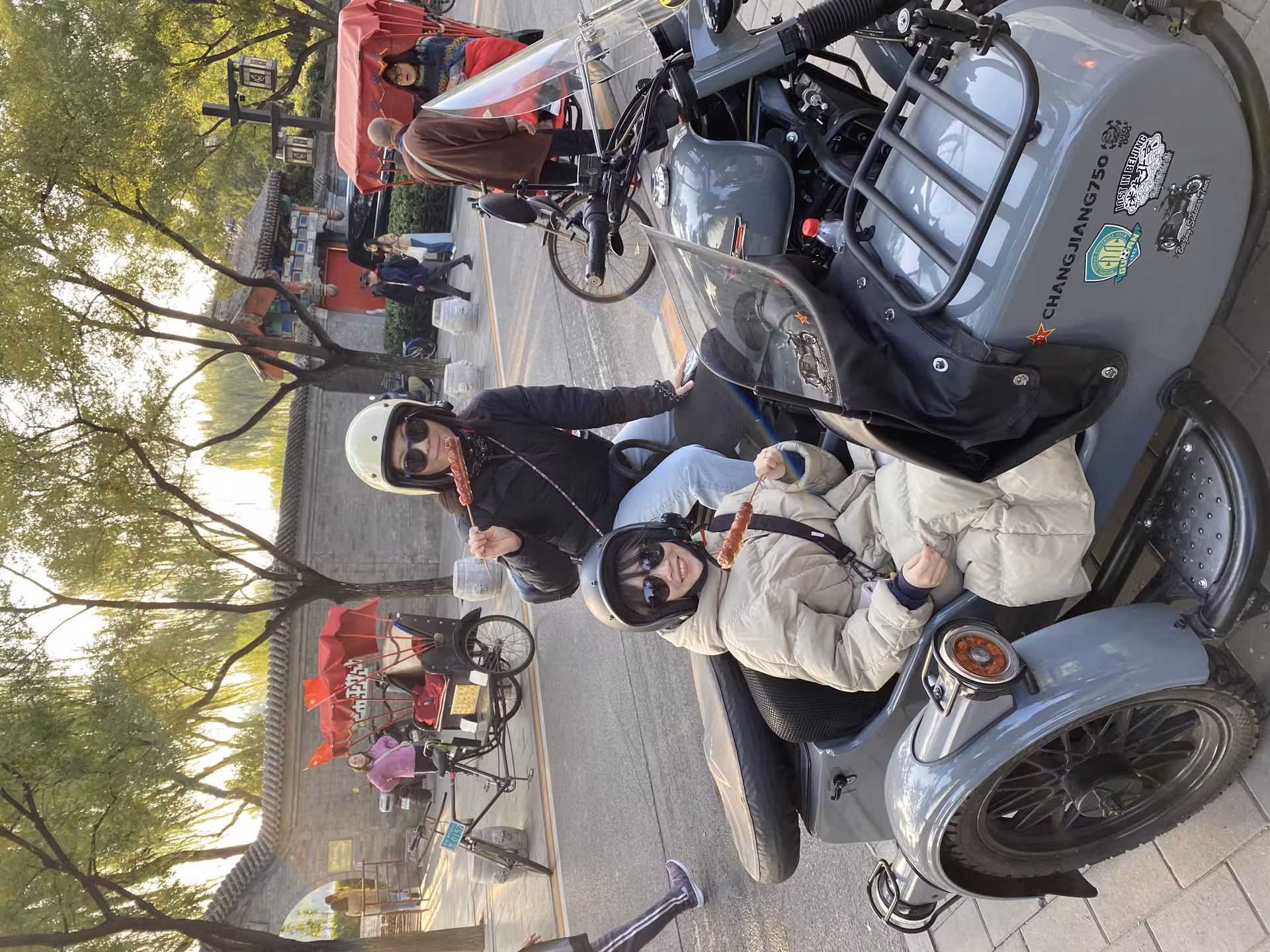 Tourists enjoying a sidecar ride while tasting local snacks in Beijing's historic streets on the Old City tour.