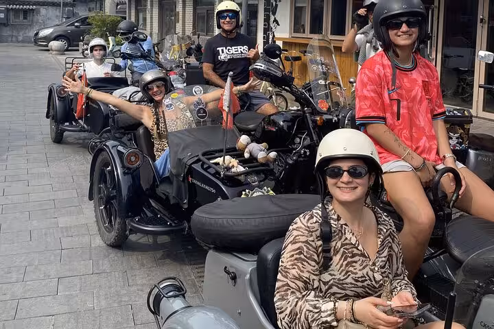 Smiling travelers enjoy a Beijing sidecar tour, capturing the excitement of exploring the city's vibrant avenues.