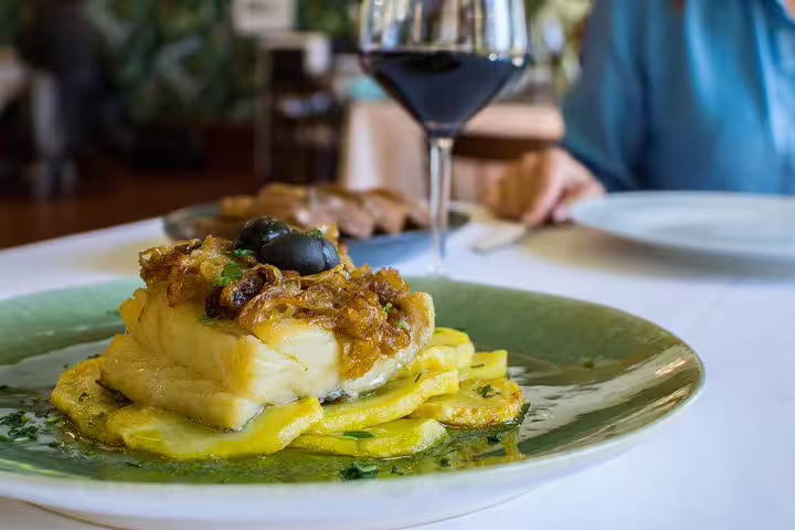 Delight in Belem's culinary heritage with a traditional Portuguese dish and wine, featured on a private day trip tour.