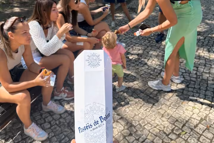 Savor delicious Pastéis de Belém while enjoying a leisurely gathering in a sunny outdoor setting.