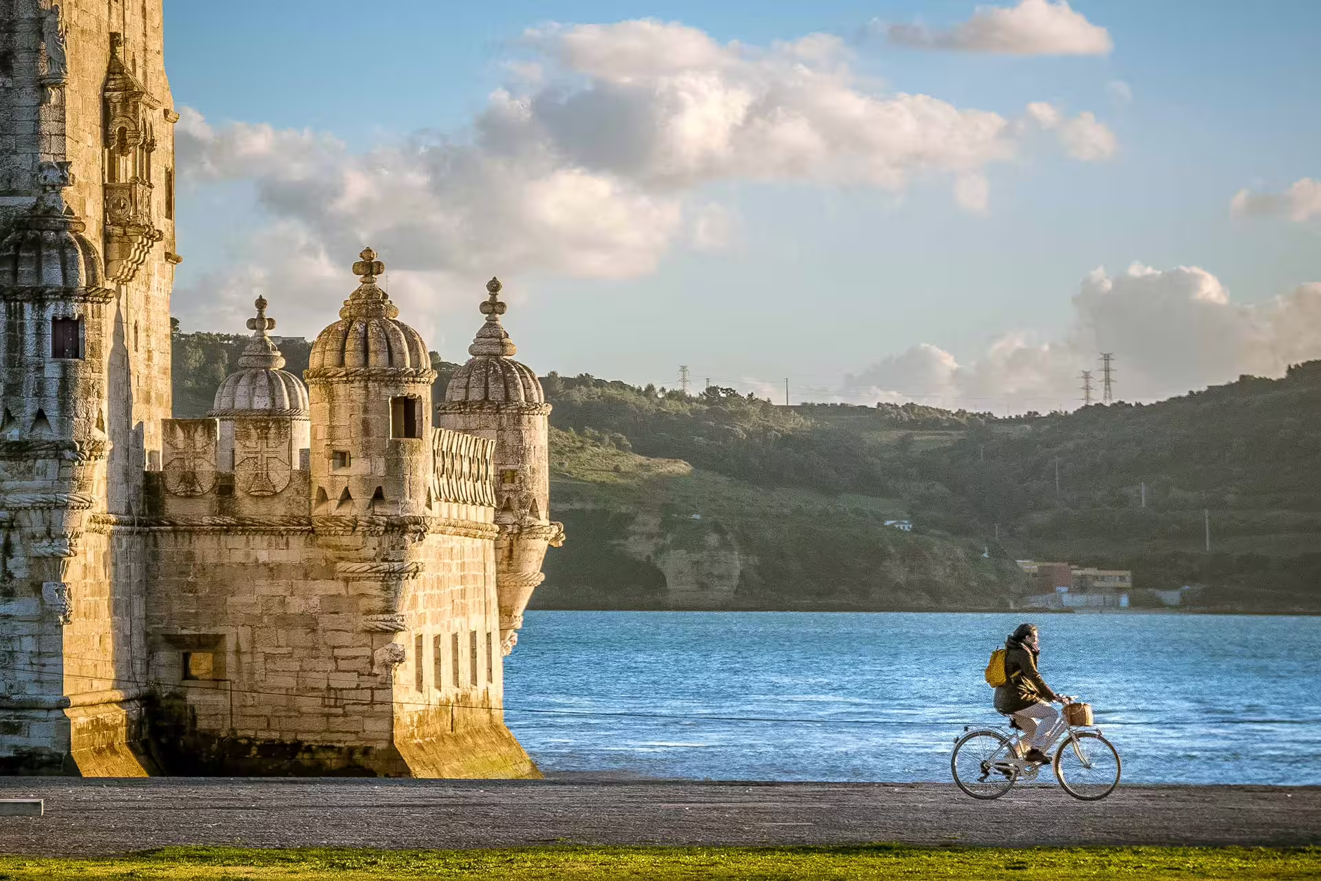 Cyclist enjoys a scenic ride by the historic Belém Tower at sunset, capturing Lisbon's vibrant atmosphere and stunning river views.