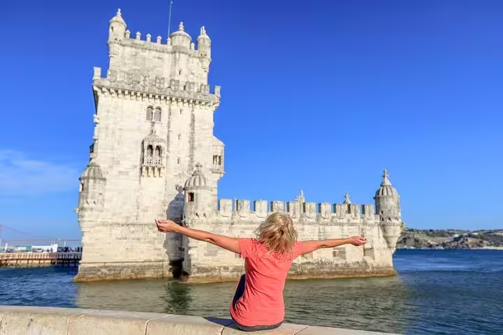 Traveler enjoys view of historic Belém Tower in Lisbon on a sunny day, part of a private day trip exploring local heritage.
