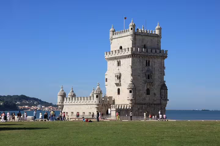 Belém Tower in Lisbon, a UNESCO World Heritage site, stands majestically by the Tagus River under a clear blue sky.