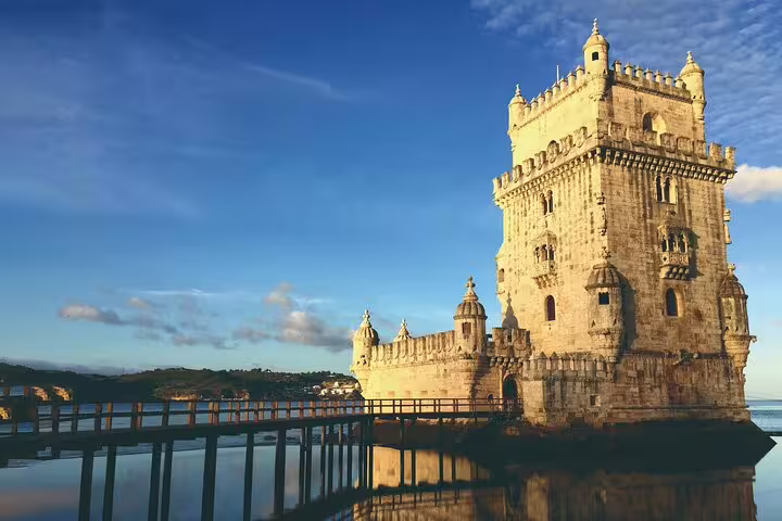Iconic Belém Tower in Lisbon, reflecting in the Tagus River under a clear blue sky, ideal for a private Lisbon tour.