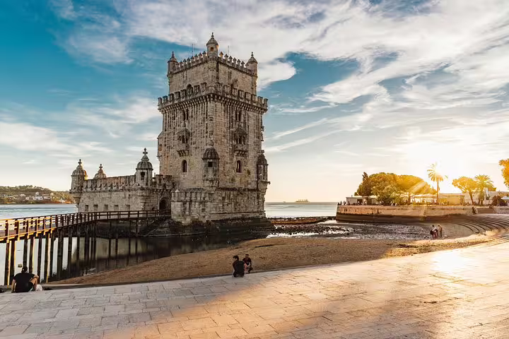 Scenic view of Belém Tower by the waterfront at sunset, a highlight of the Lisbon Tuk Tuk tour experience.