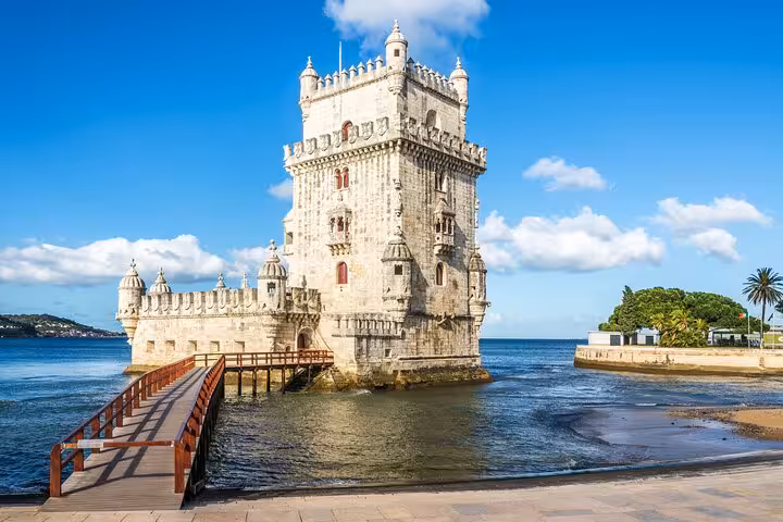 The iconic Belém Tower standing majestically by the Tagus River, showcasing Manueline architecture under a sunny sky.