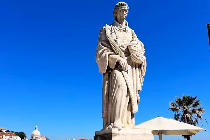 Stone statue at Belém waterfront under blue sky, scenic stop on a 4-hour private Tuk Tuk tour Lisbon