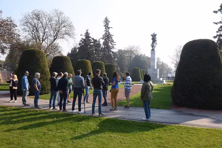 Tour group exploring a manicured garden with a monument in Belgrade, featured in the Belgrade Big Tour.
