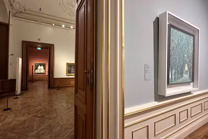 Interior view of the Belvedere Museum with framed artwork and elegant wood-paneled doors in Vienna.