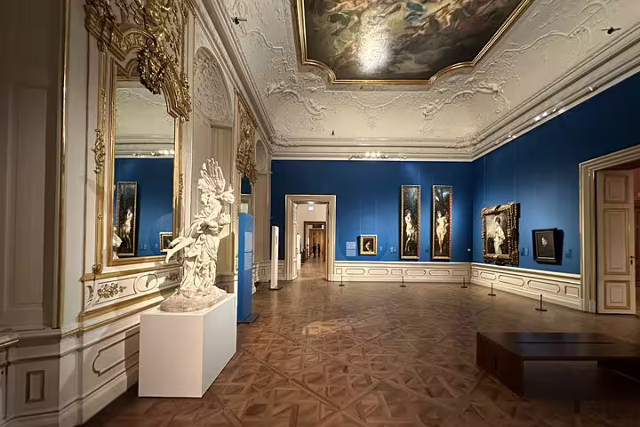 Ornate baroque room at the Belvedere Palace in Vienna, featuring classical sculptures and rich, blue walls.