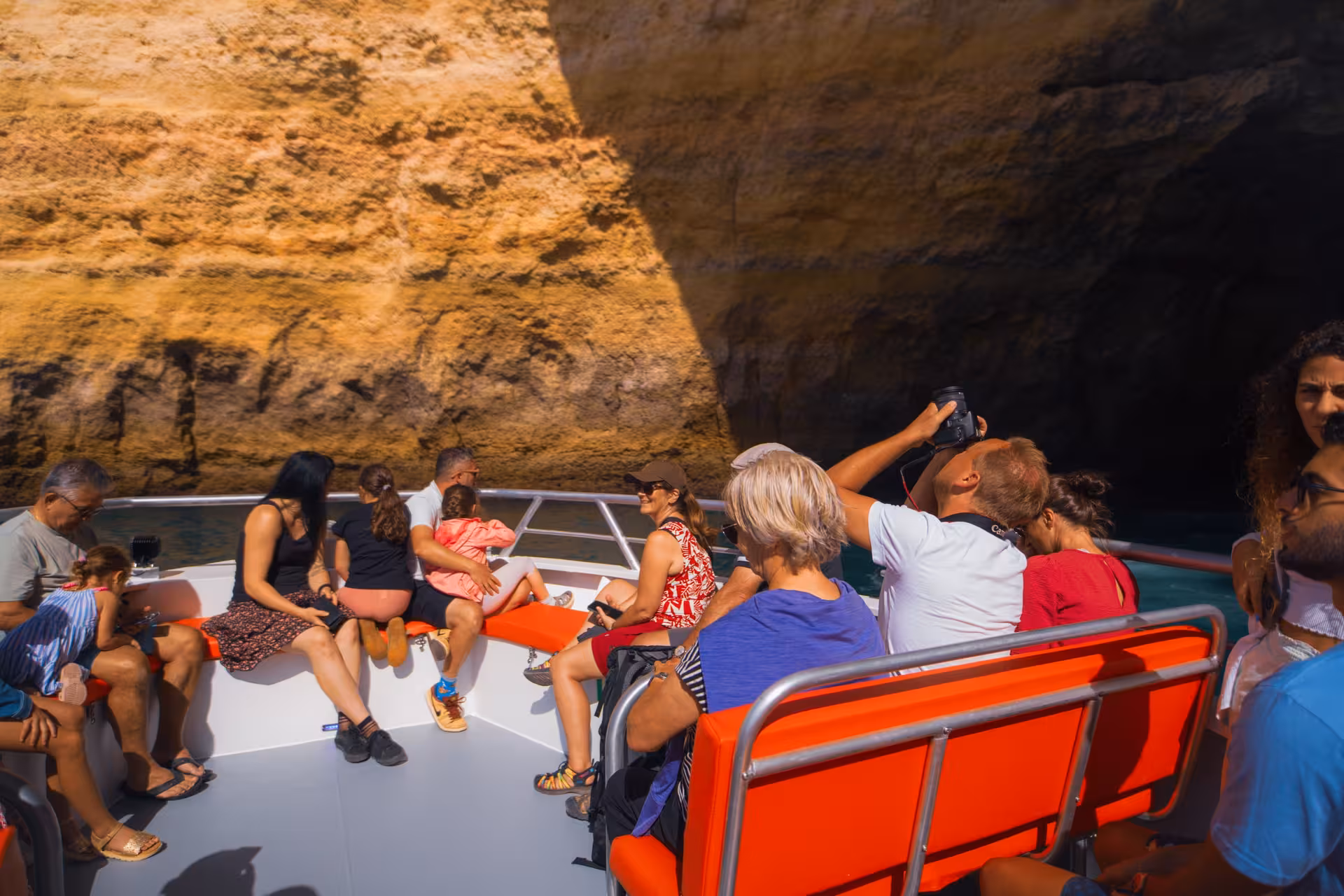Tourists exploring Benagil Cave on a full-day Algarve boat tour amid stunning golden limestone cliffs