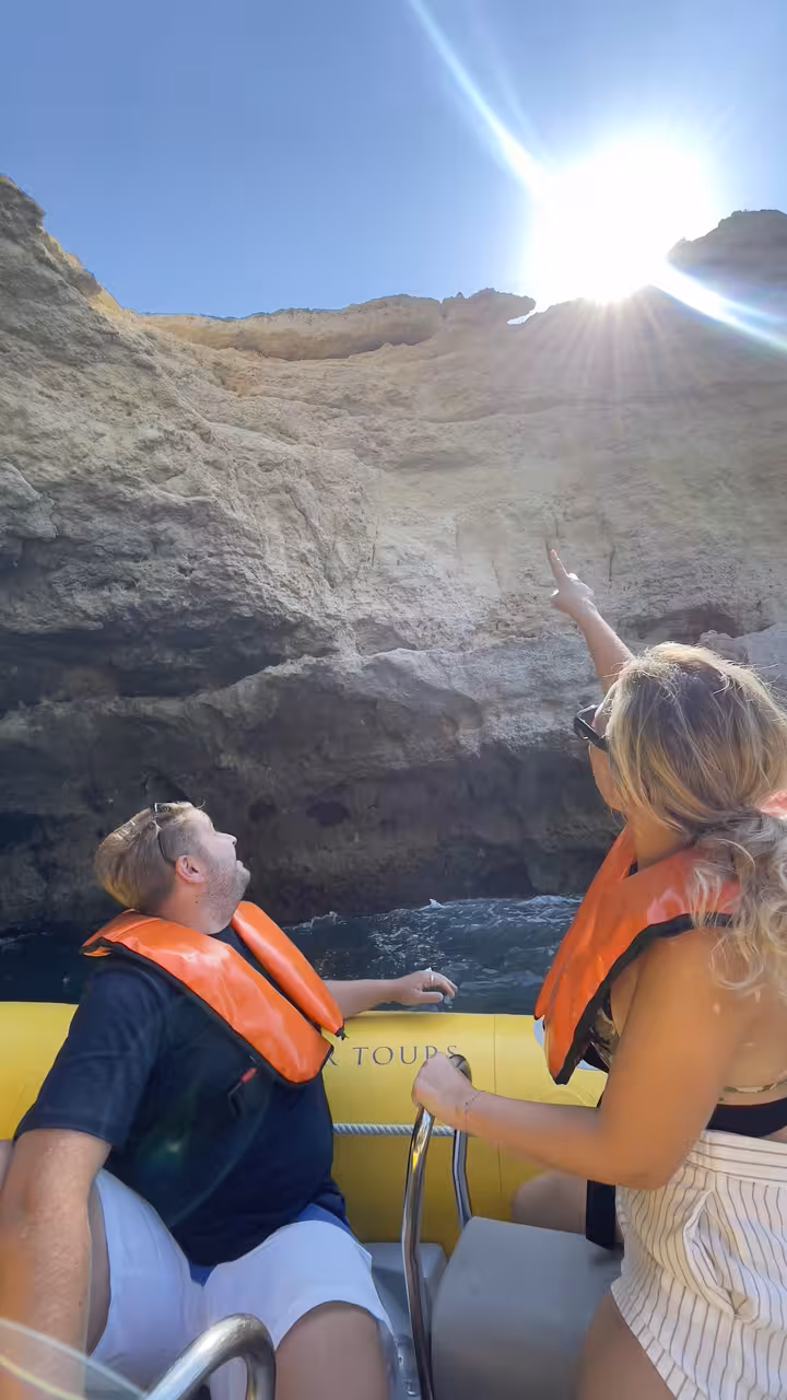 Guests in life jackets on a speedboat exploring Algarve sea caves and dramatic cliffs on a coastal tour
