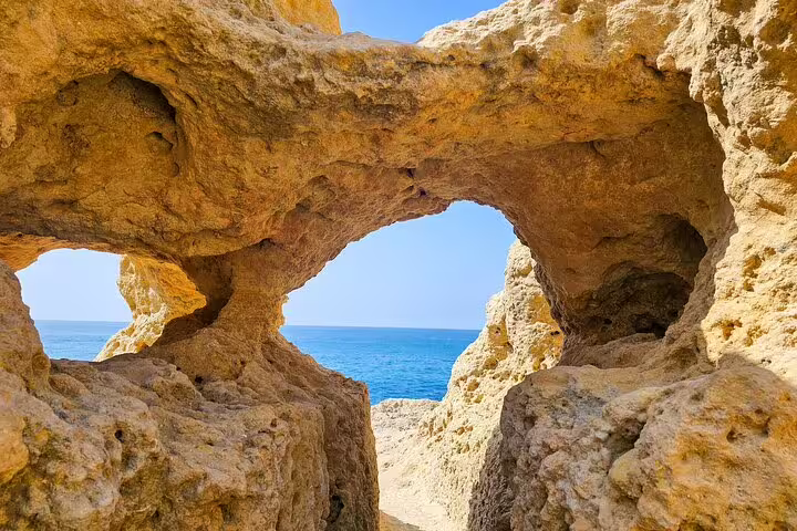 Natural rock formation with arch framing ocean view on Algarve Coast tour from Faro.