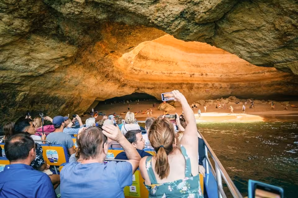 Visitors capture stunning views of the Algarve's famous Benagil Cave from a boat tour, highlighting natural beauty.