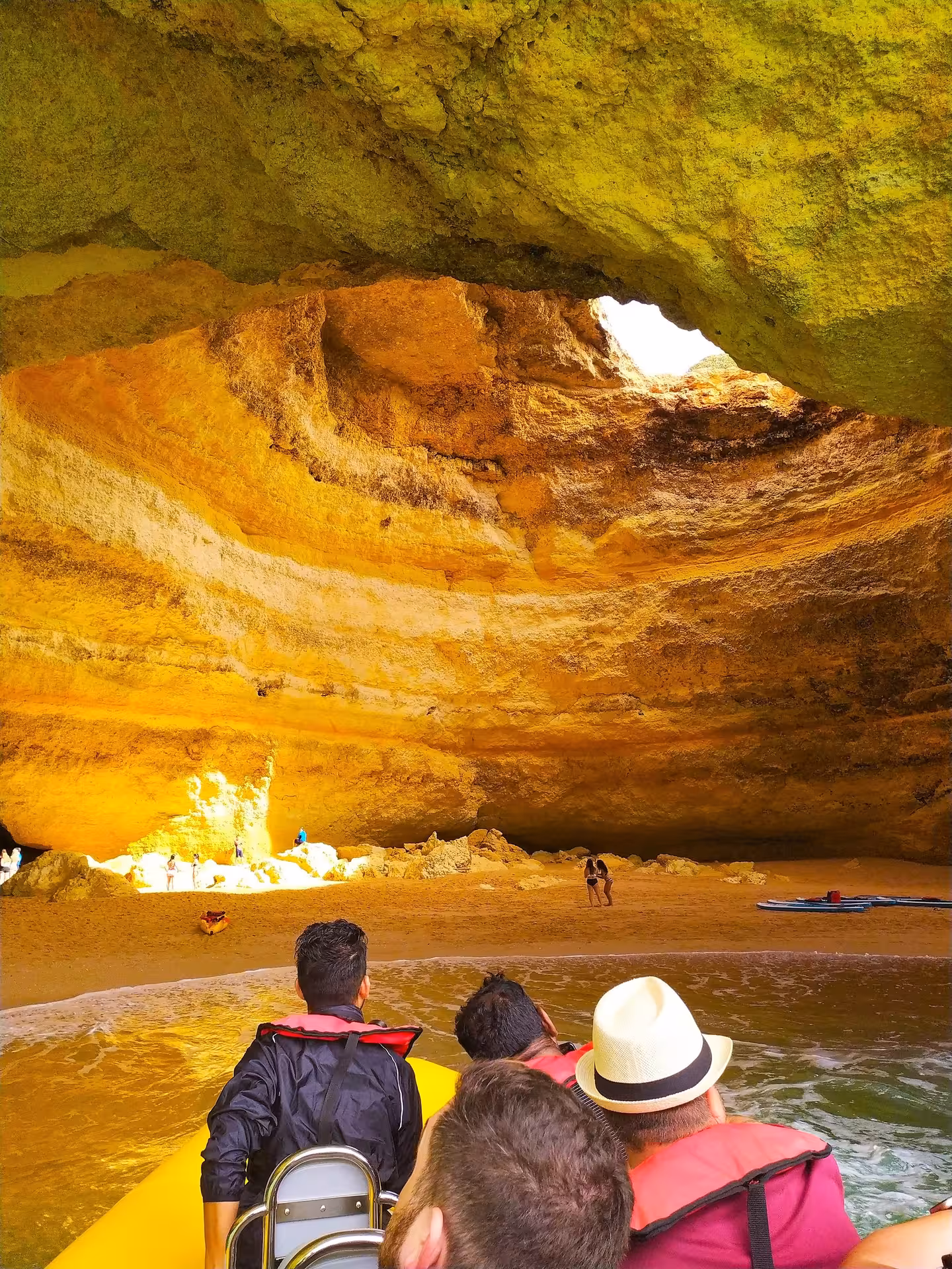 Visitors on Benagil cave boat tour landing on hidden Algarve beach under golden rock dome, Portugal coastal excursion