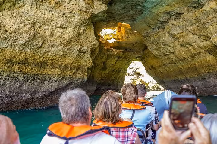 Boat entering Algarve sea cave arch near Benagil, small group tour from Lisbon with guide and cruise