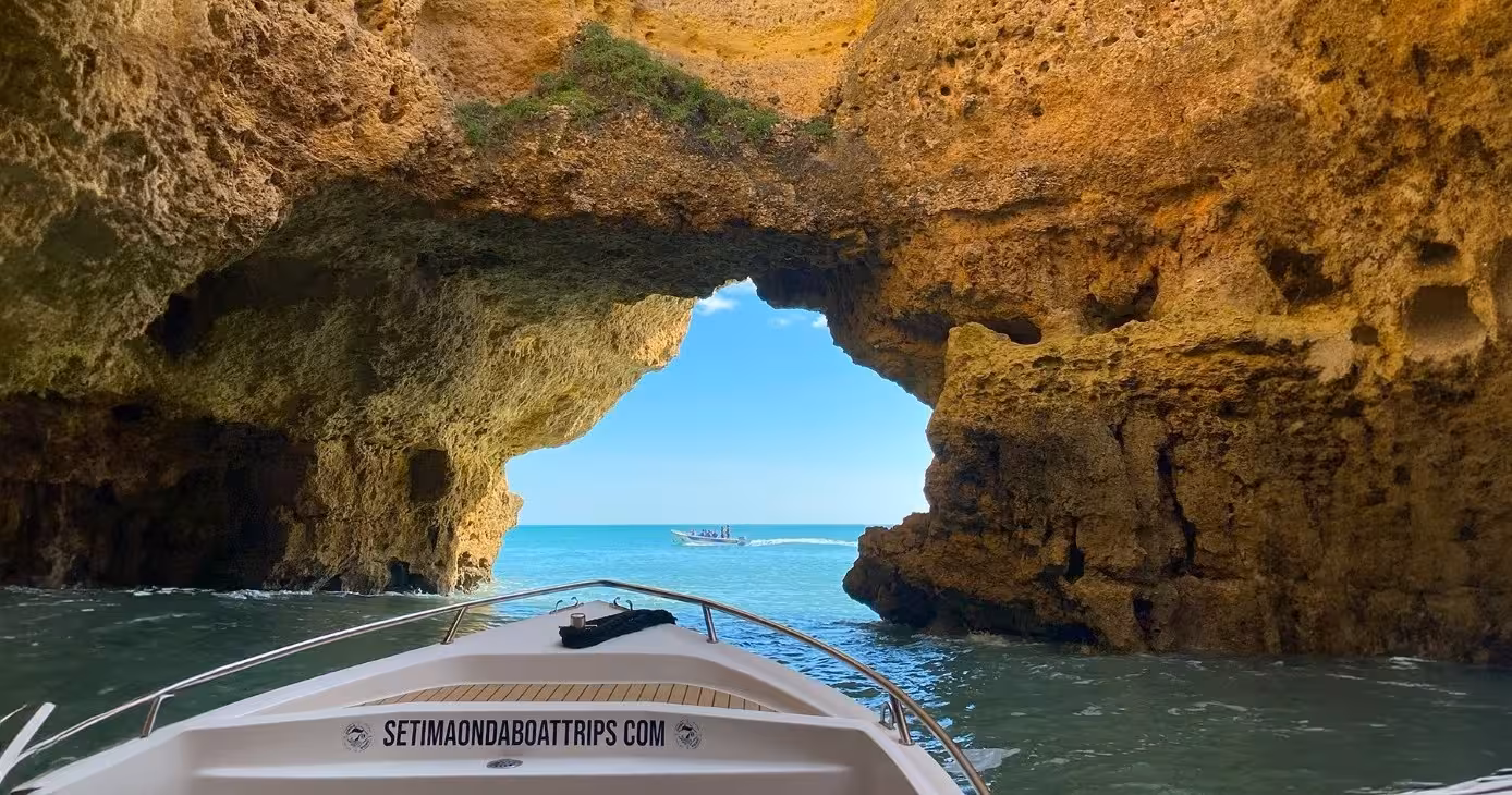 View from a Benagil cave boat tour looking out to the bright blue Algarve sea framed by golden rock arches