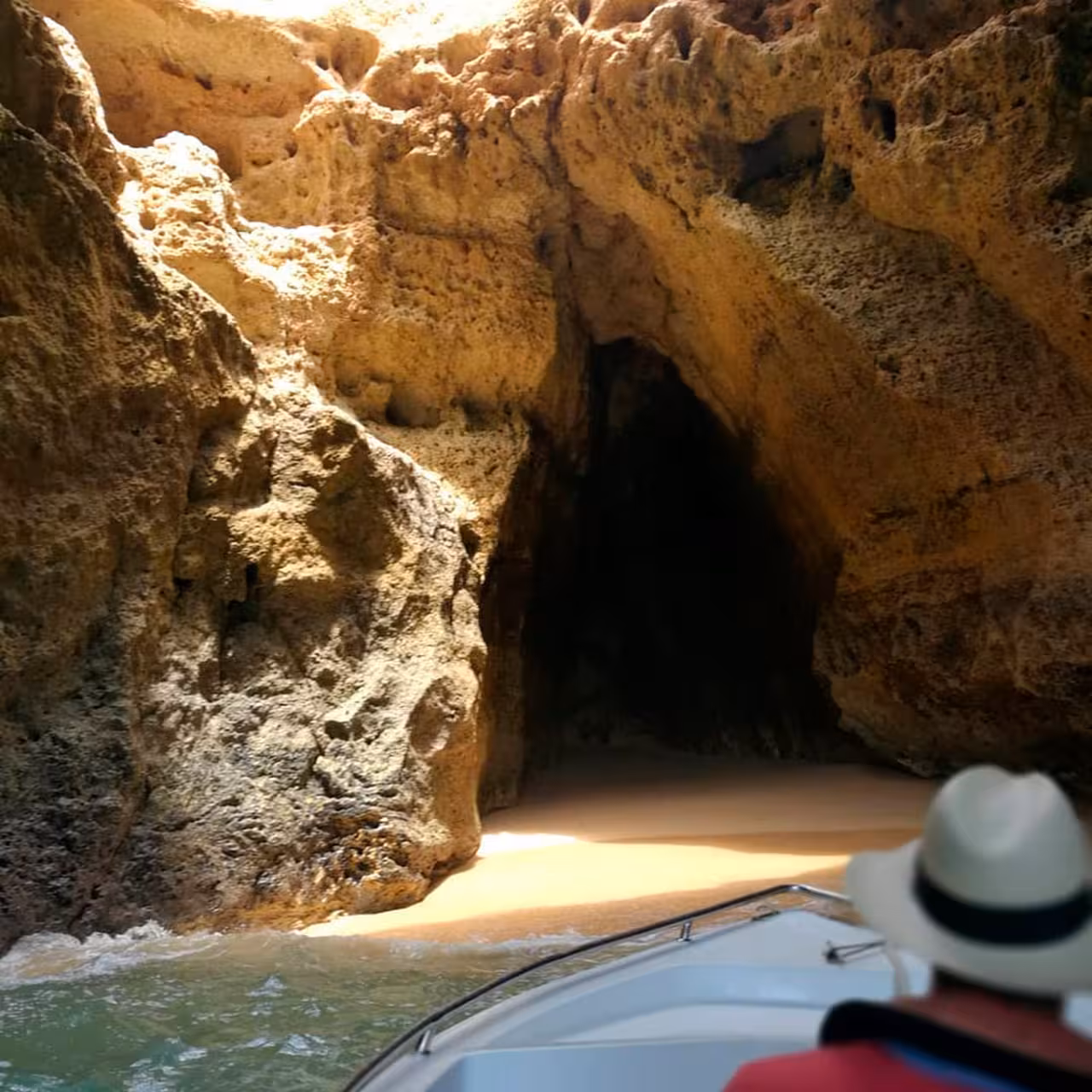 Tourist on a boat approaching the stunning Benagil Cave's sandy entrance from Carvoeiro, Algarve.