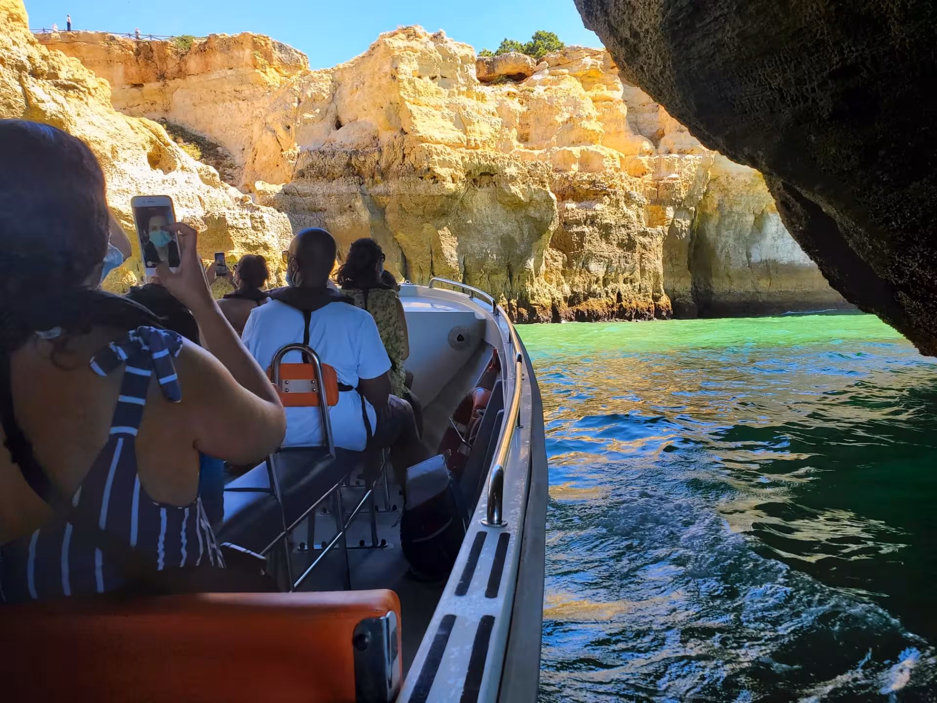 Tourists explore Benagil Cave by boat on a scenic tour from Portimão, highlighting Algarve's stunning coastal views.