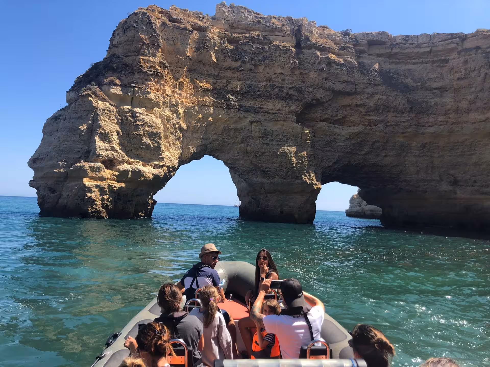 Tourists on a boat exploring the stunning rock formations of Benagil Cave on a sunny day in Algarve, Portugal.